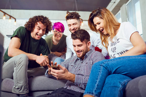 Group of friends laughing and sharing something on a phone